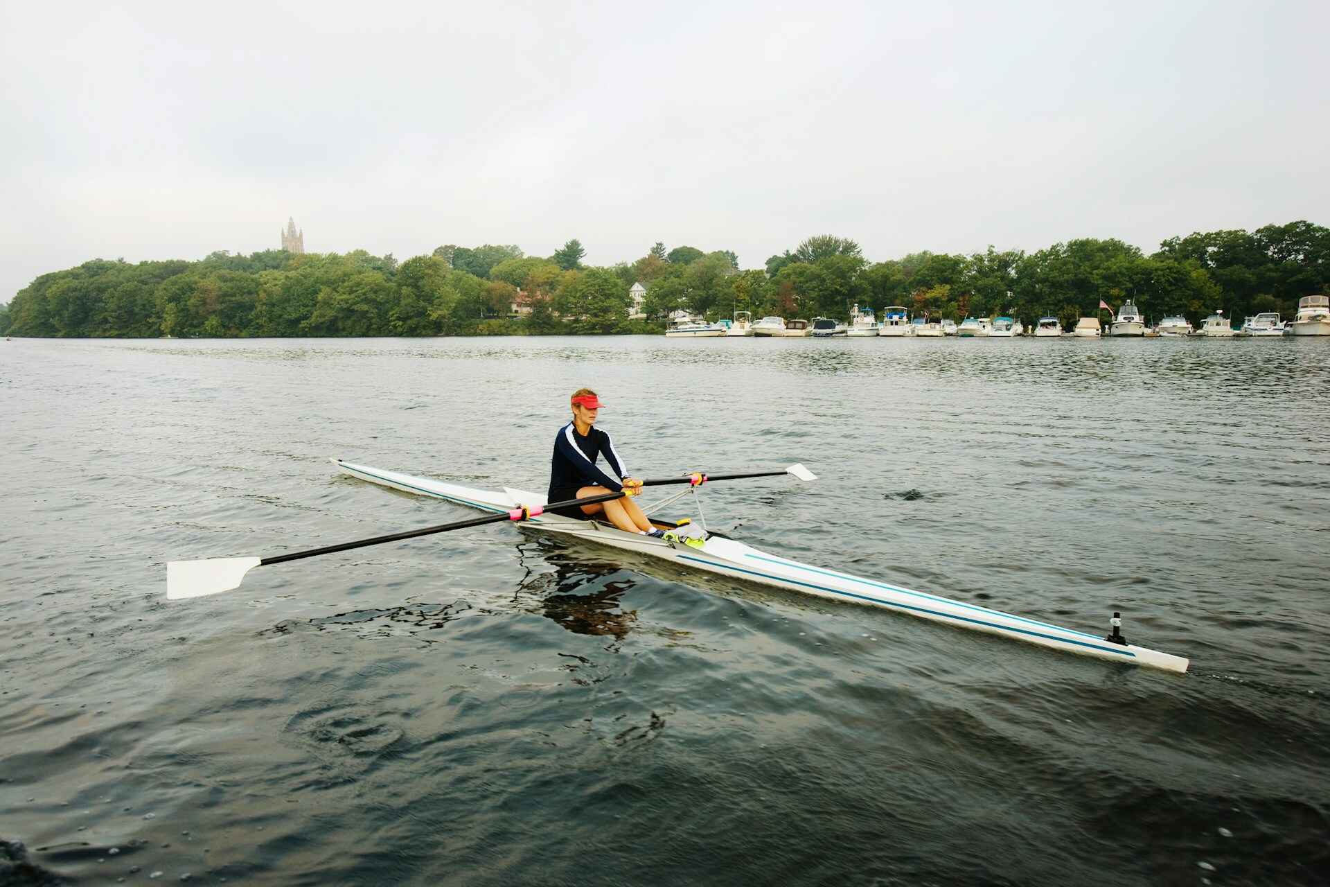 A person rowing on a calm lake, illustrating the full-body workout and stamina-building aspects of rowing