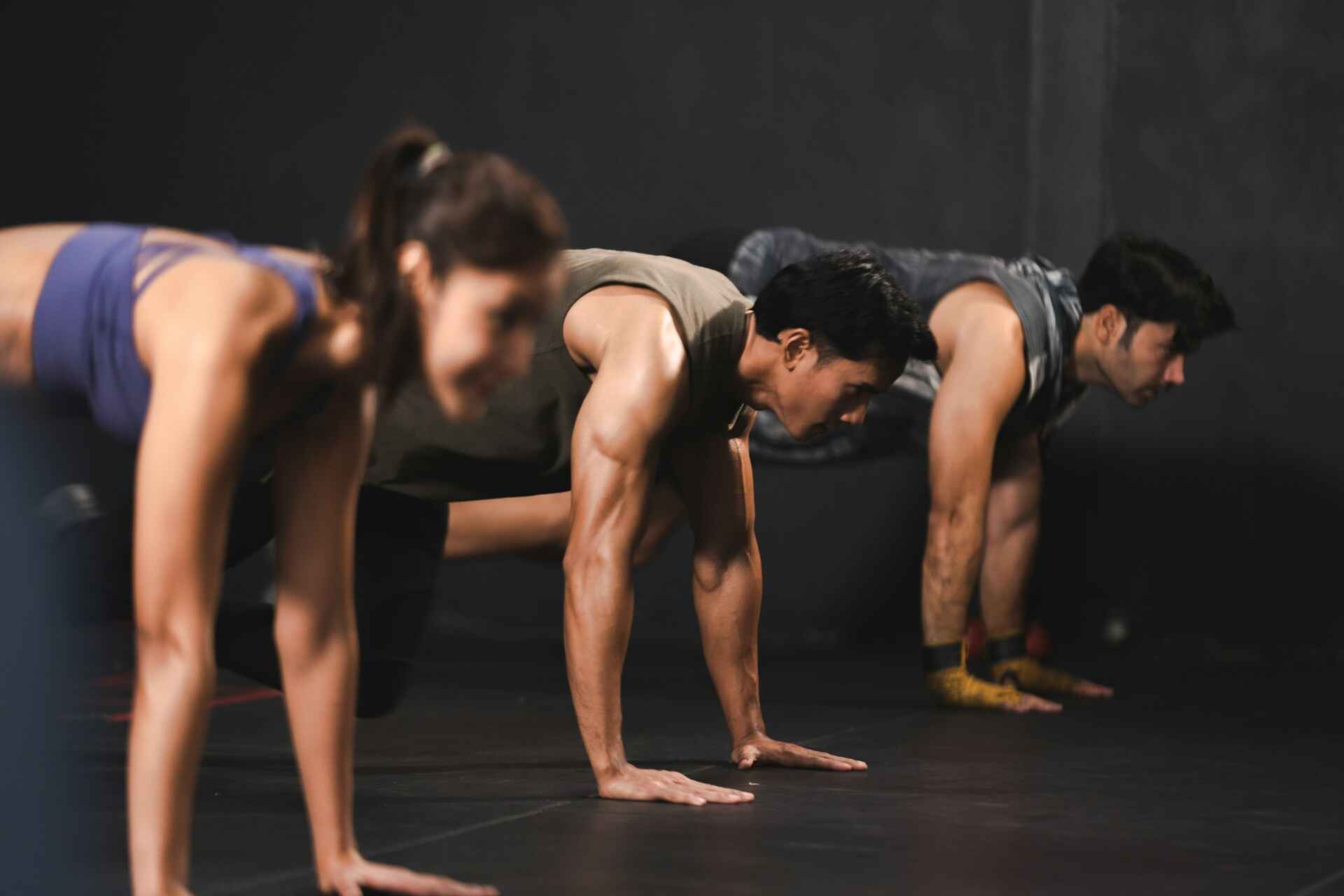 A group of people performing high-intensity exercises like burpees and sprints in a gym, demonstrating the quick bursts of activity typical of HIIT workouts