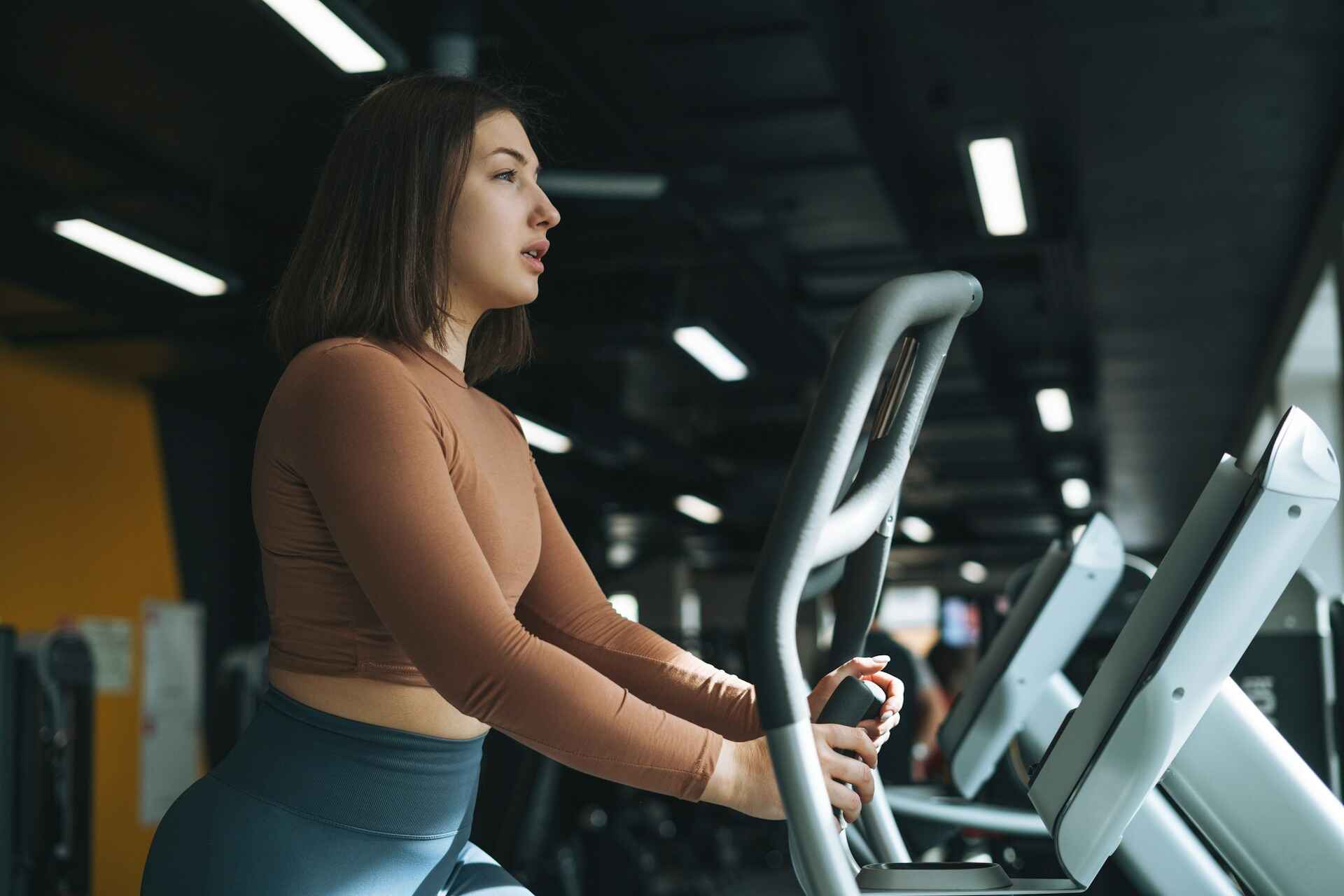 A person using an elliptical machine in a gym, showing the low-impact cardio benefits of elliptical training for building stamina.