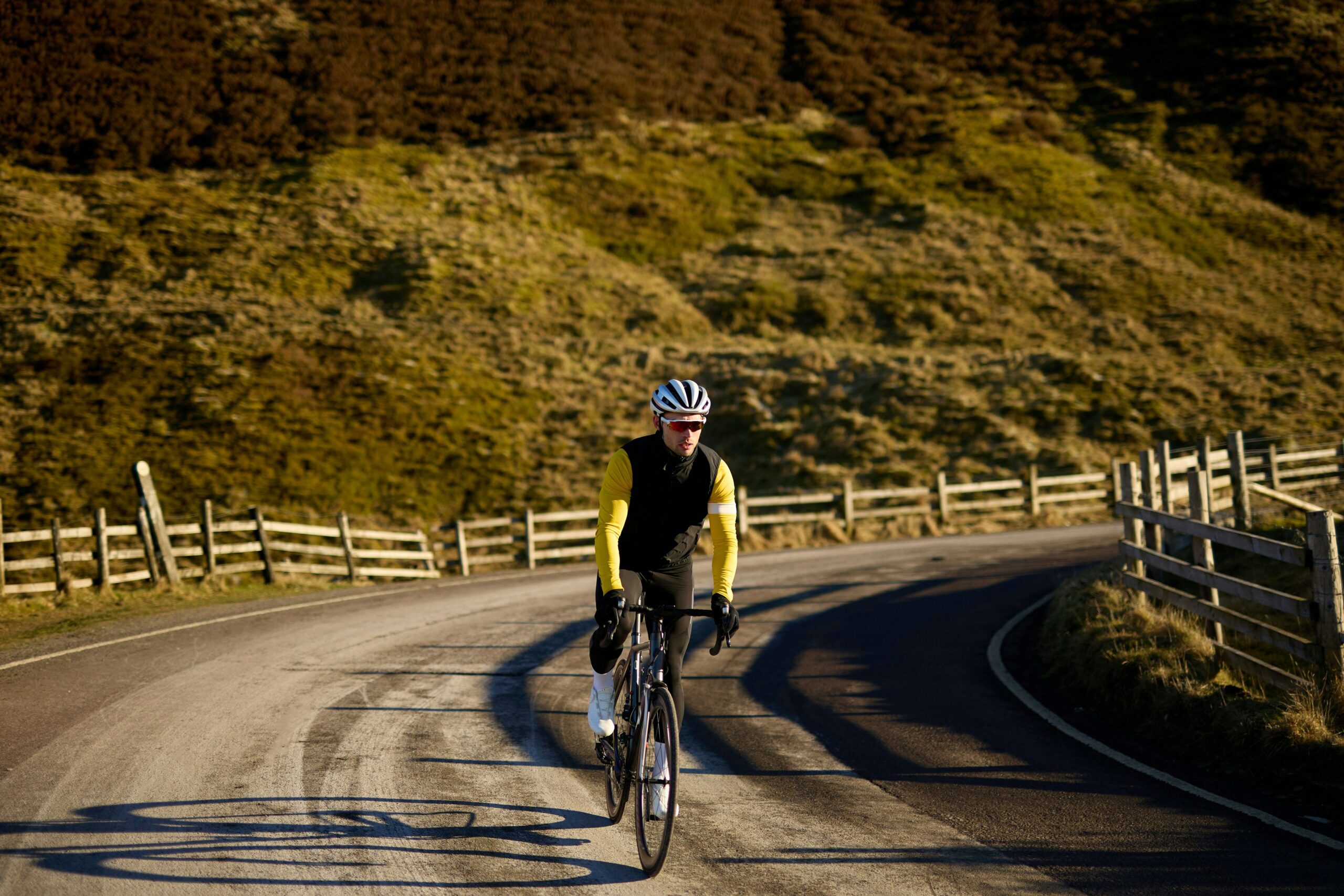 "A cyclist riding on a road with hills in the background, emphasizing the low-impact nature and endurance benefits of cycling