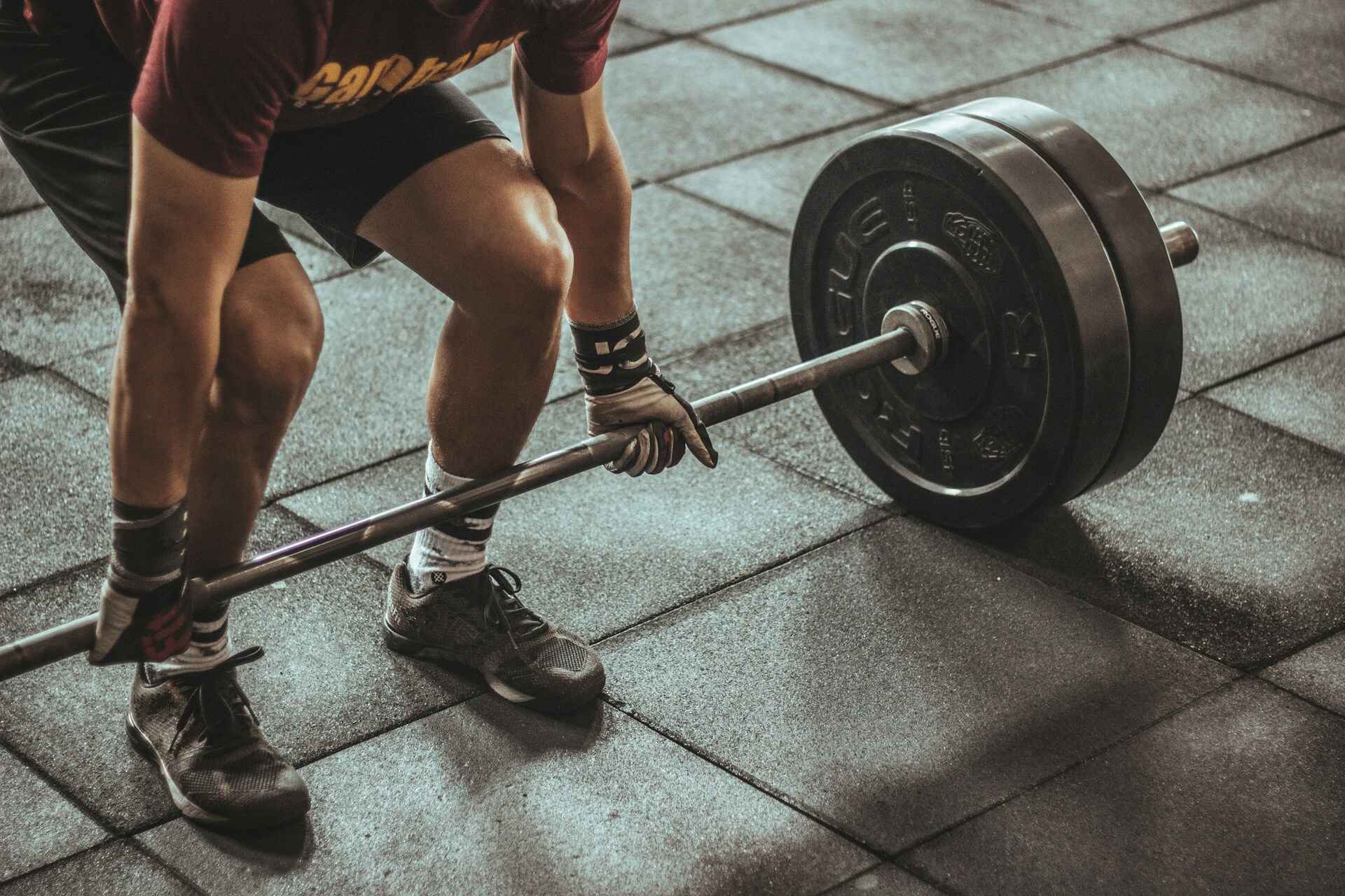 A person lifting weights in a gym, focusing on compound movements like squats and deadlifts to build both strength and stamina