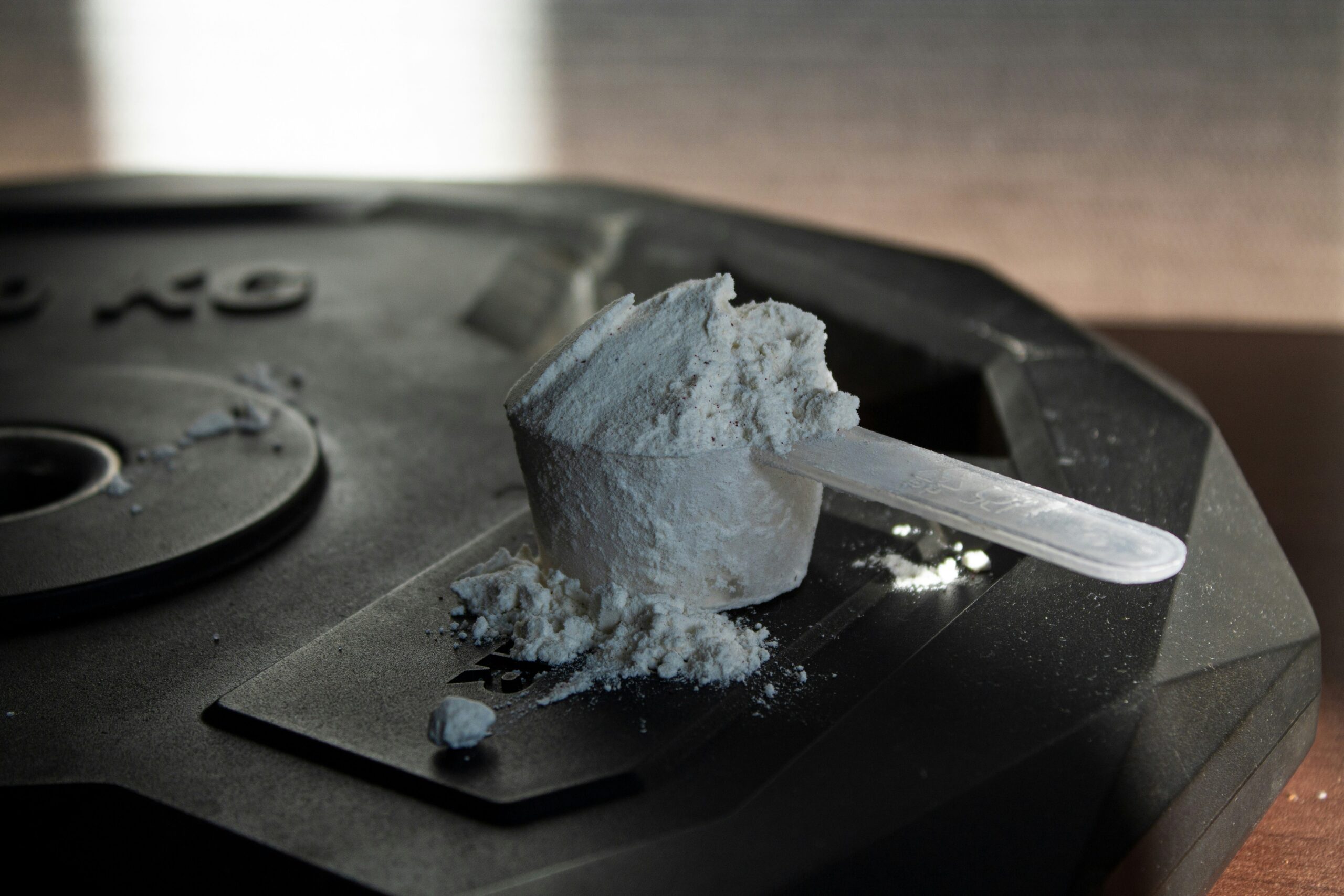 A container of creatine with a scoop measuring 5 grams, representing the loading phase where higher doses are taken initially to saturate muscles