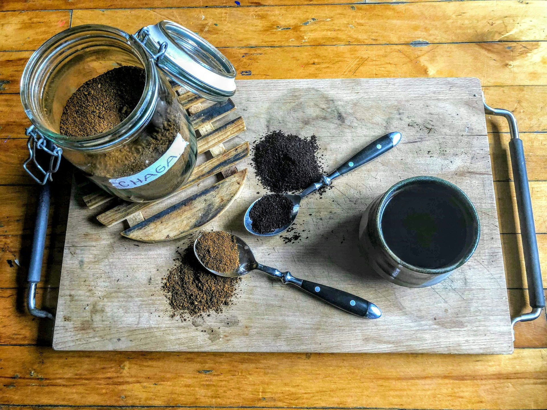 A cup of mushroom coffee on a wooden table surrounded by fresh mushrooms and coffee beans