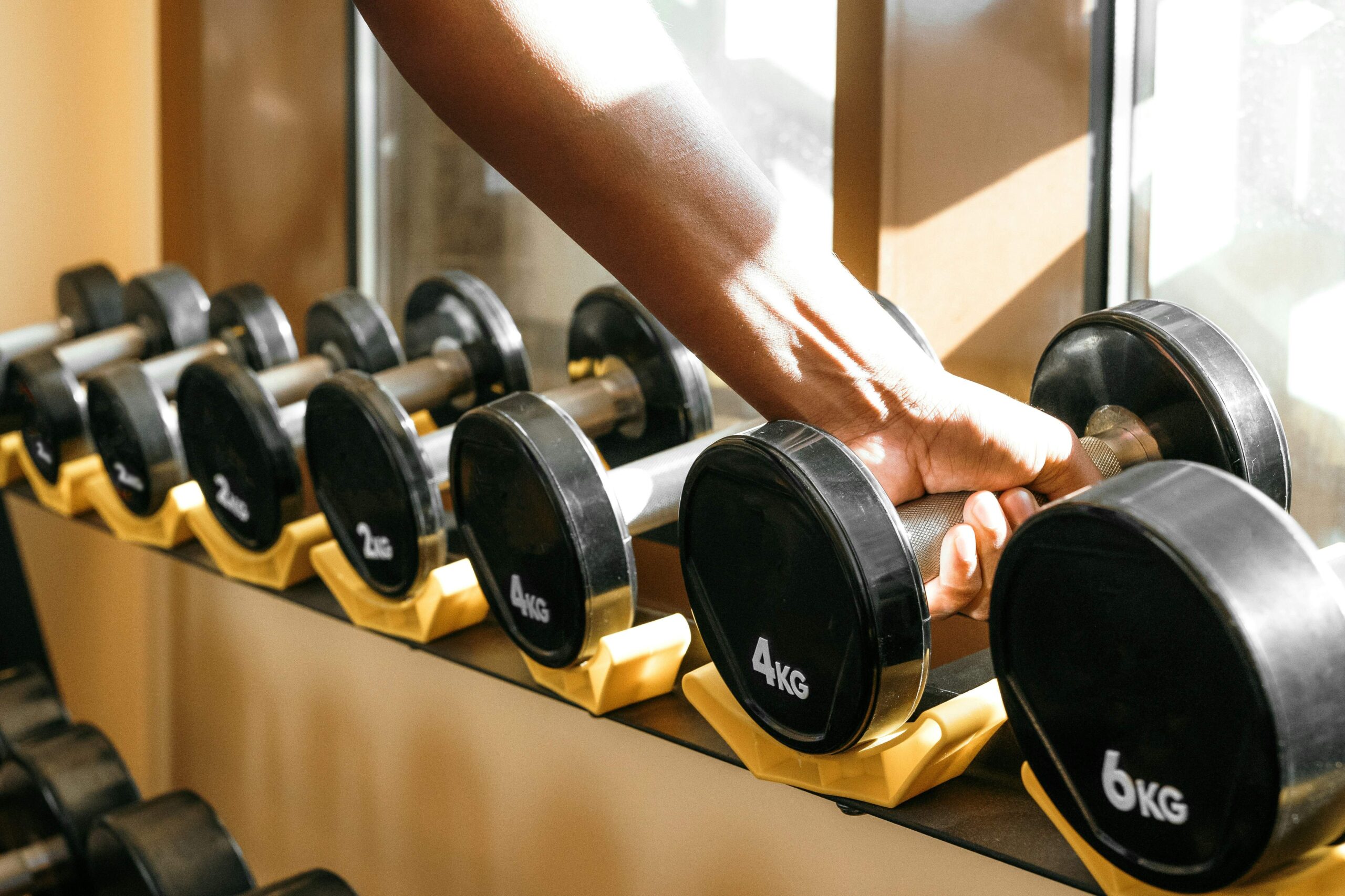 Close-up of a person struggling to lift weights, showing frustration, highlighting the challenge of hitting a fitness plateau