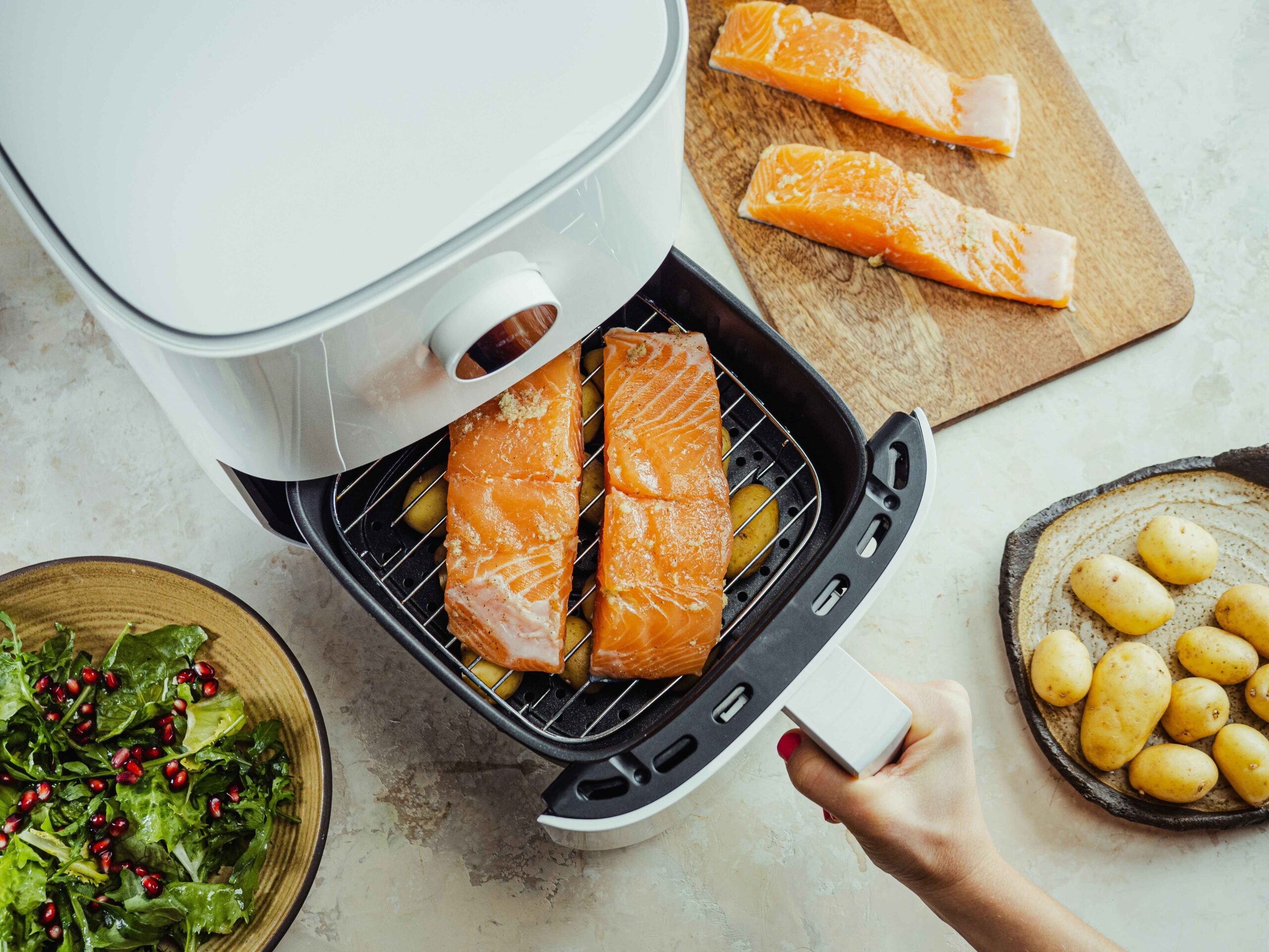 Raw salmon fillet with broccoli and carrots arranged in an air fryer basket, ready for cooking.