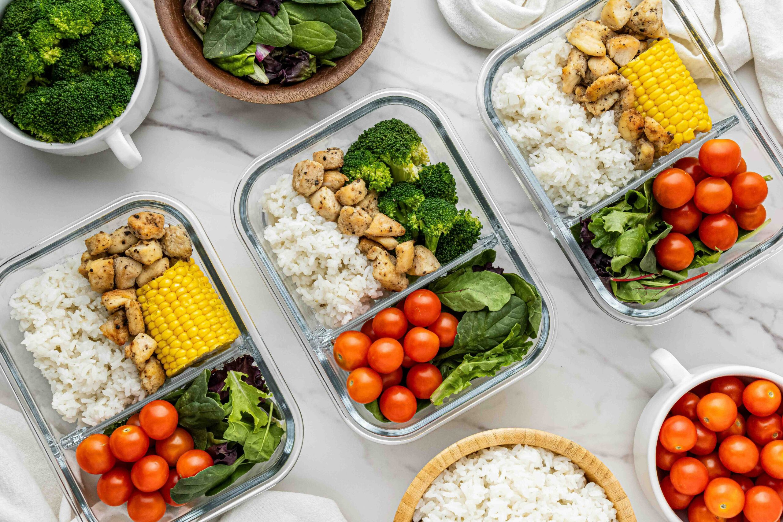 Image of a well-organized meal prep table with containers filled with vegetables, grains, and proteins: